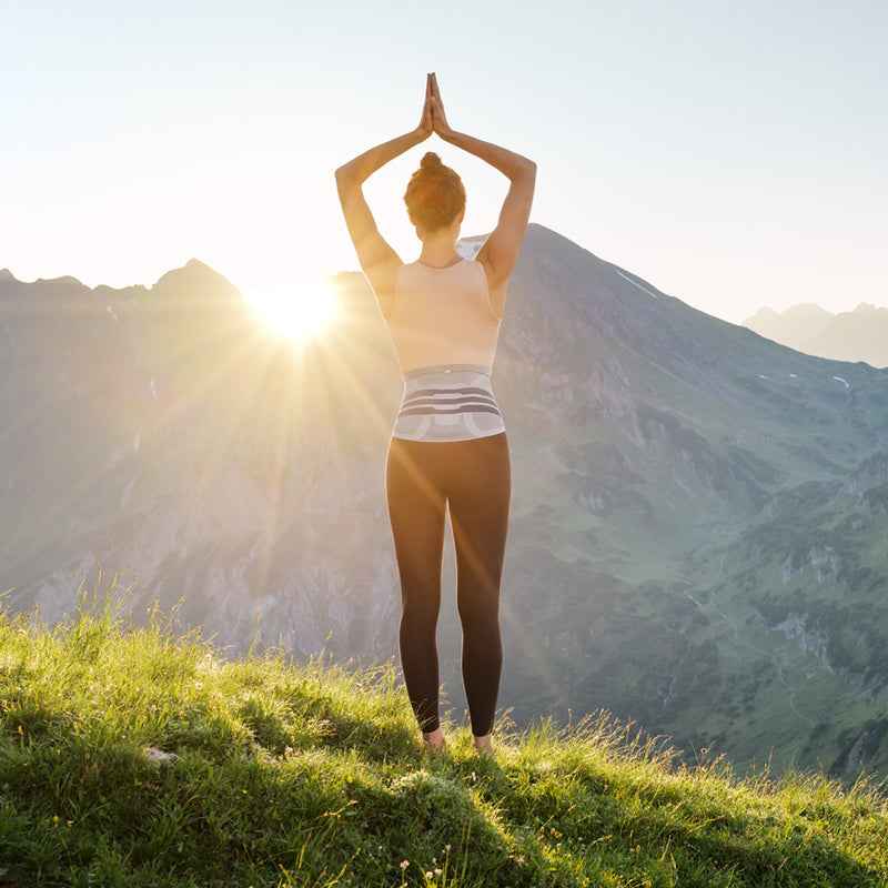 Woman stretching outdoors at sunrise wearing a Bauerfeind LumboTrain back support